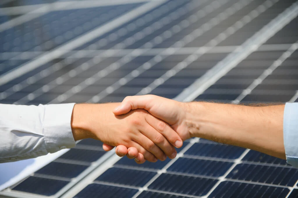 two-people-having-a-shaking-hands-against-solar-pa